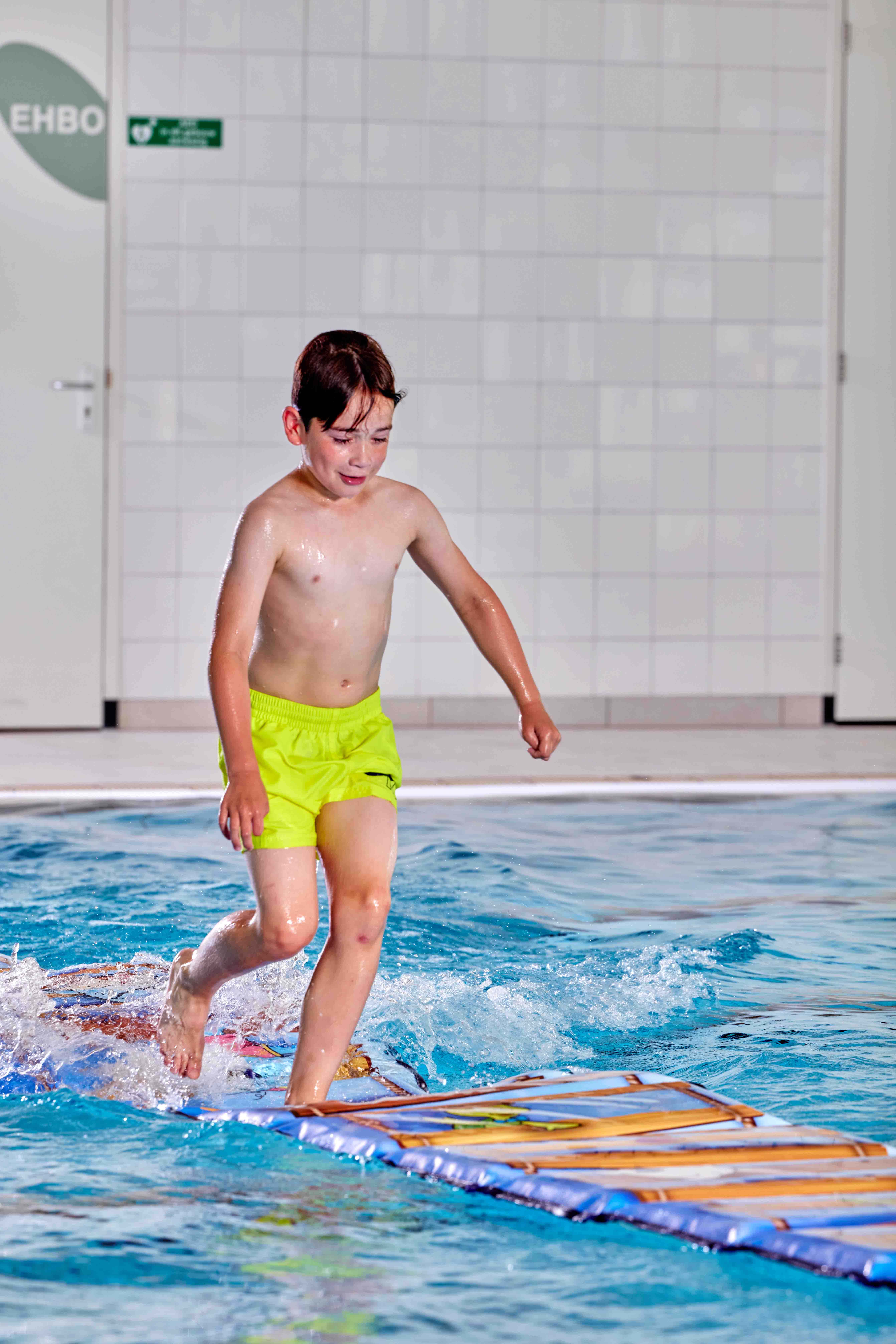 Tijdens Vrijzwemmen in het zwembad van Optisport rent een jongetje behendig over een lange mat die over het water heen is gelegd… zou hij de overkant halen zonder te vallen? 